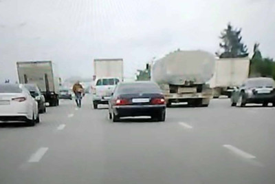 Piyada maşınların intensiv hərəkət etdiyi yol ilə gəzə-gəzə gedib